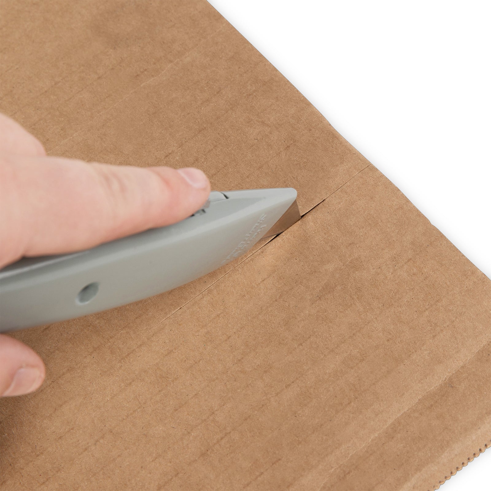 a hand using a box cutter to cut cardboard | city business shipping