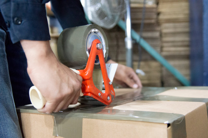 Person taping a box shut - City Business Shipping