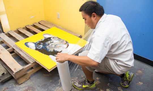 a person packaging a painting - City Business Shipping