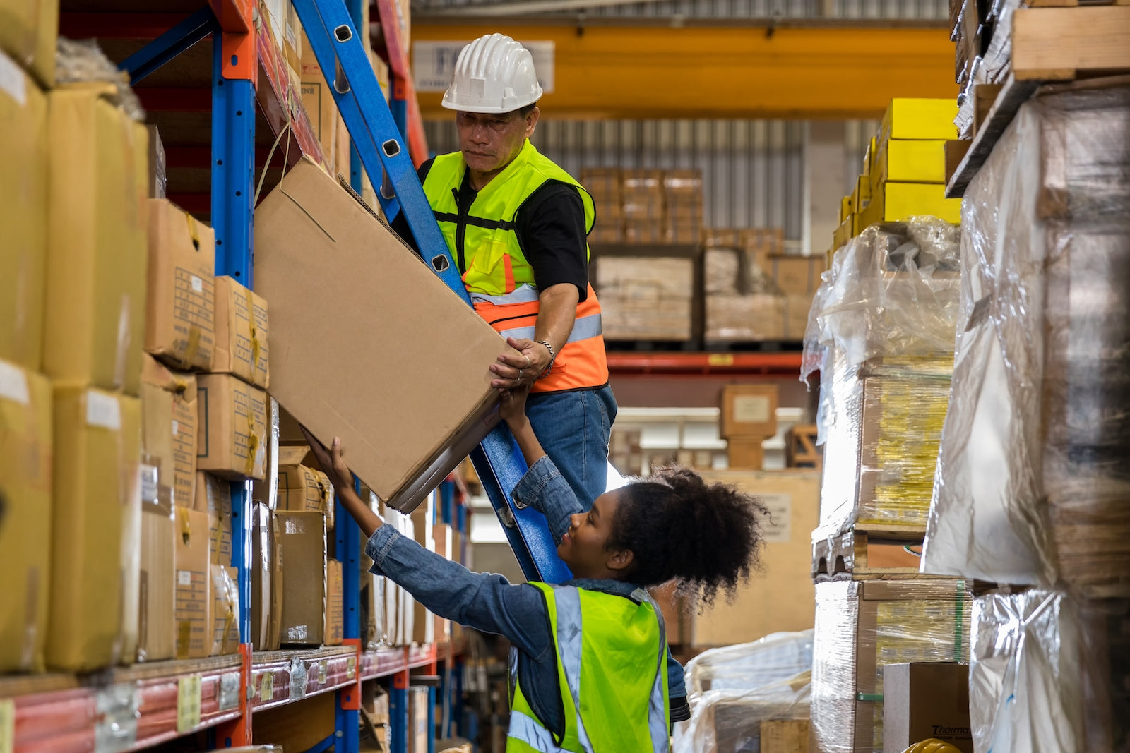 two people pulling a package from the shelf in a warehouse - City Business Shipping